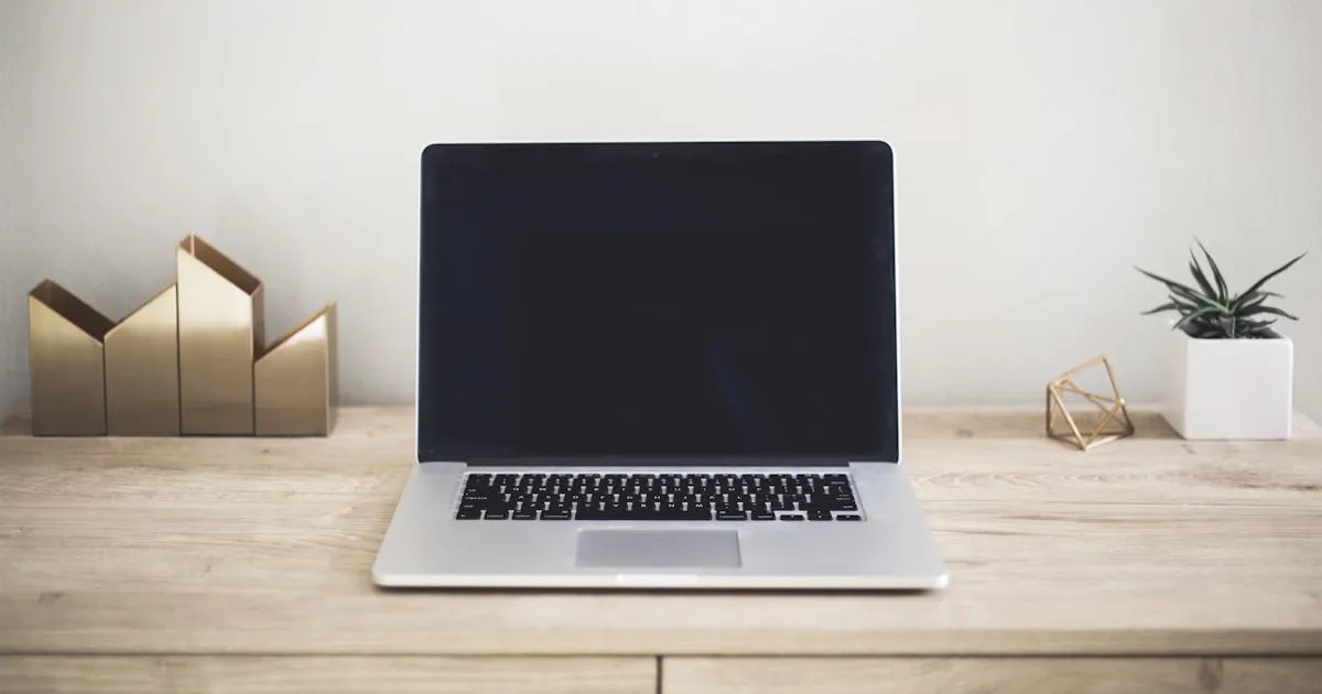 Laptop na biurku w profesjonalnym środowisku biurowym, obok notatnik i długopis, symbolizujące przemyślany zakup sprzętu biznesowego.